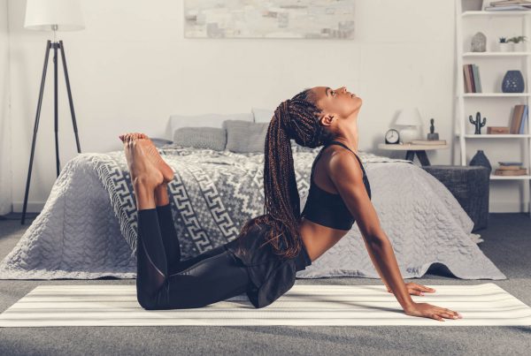 Creating a Fitness Plan That Works for You - A woman practices yoga in her bedroom