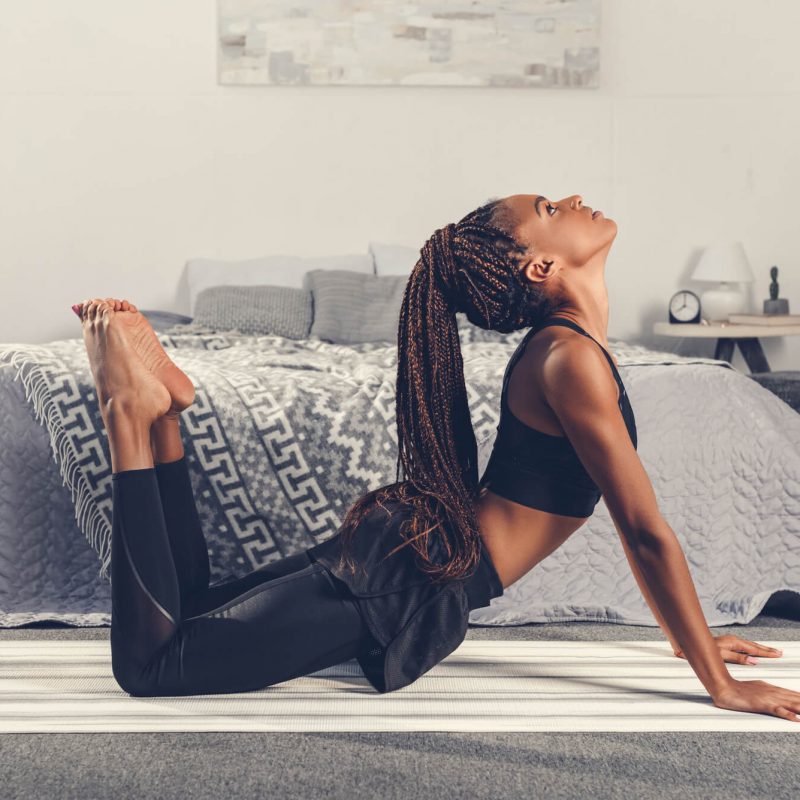 Creating a Fitness Plan That Works for You - A woman practices yoga in her bedroom