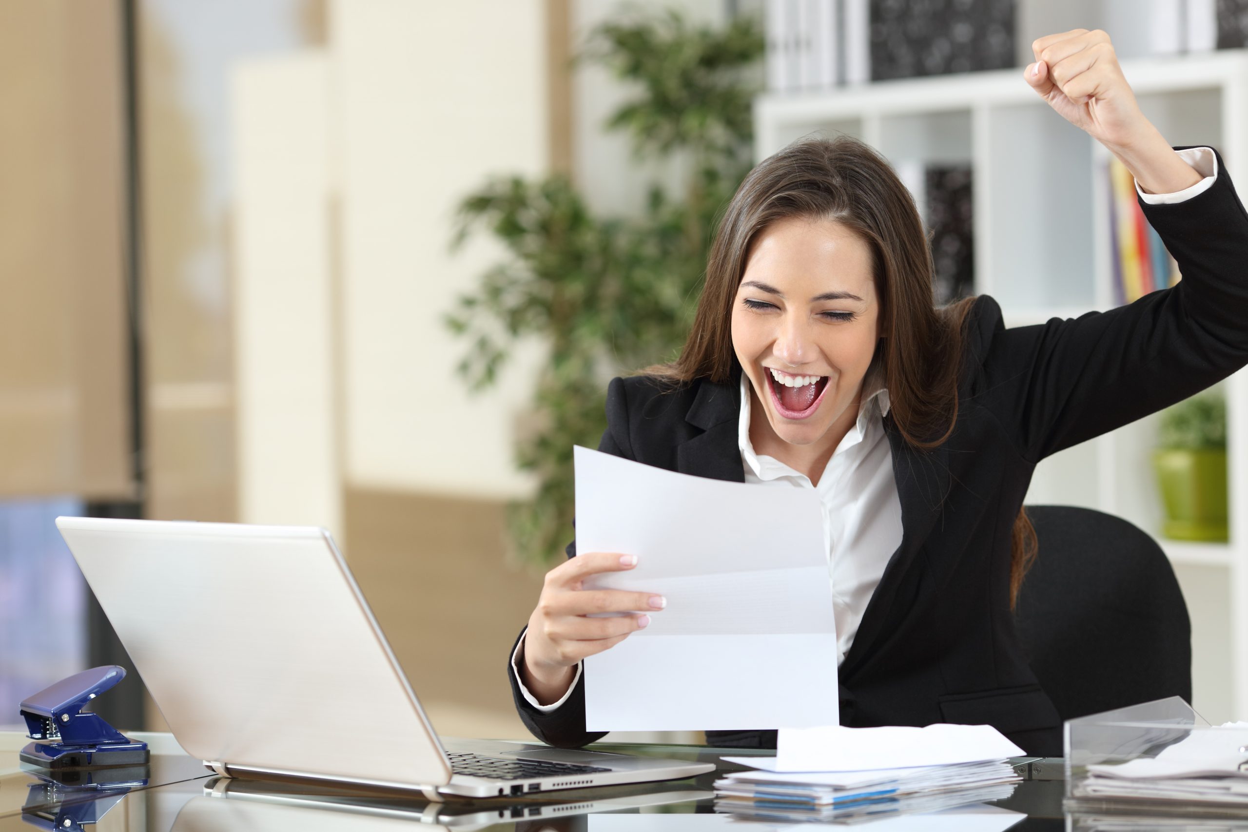 girl at desk happily pumping fist in air for good credit