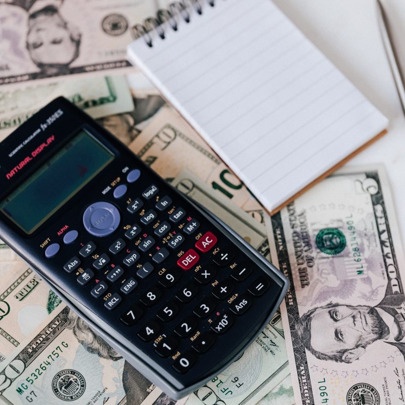 Stack of cash with a calculator: 7 common finacial mistakes