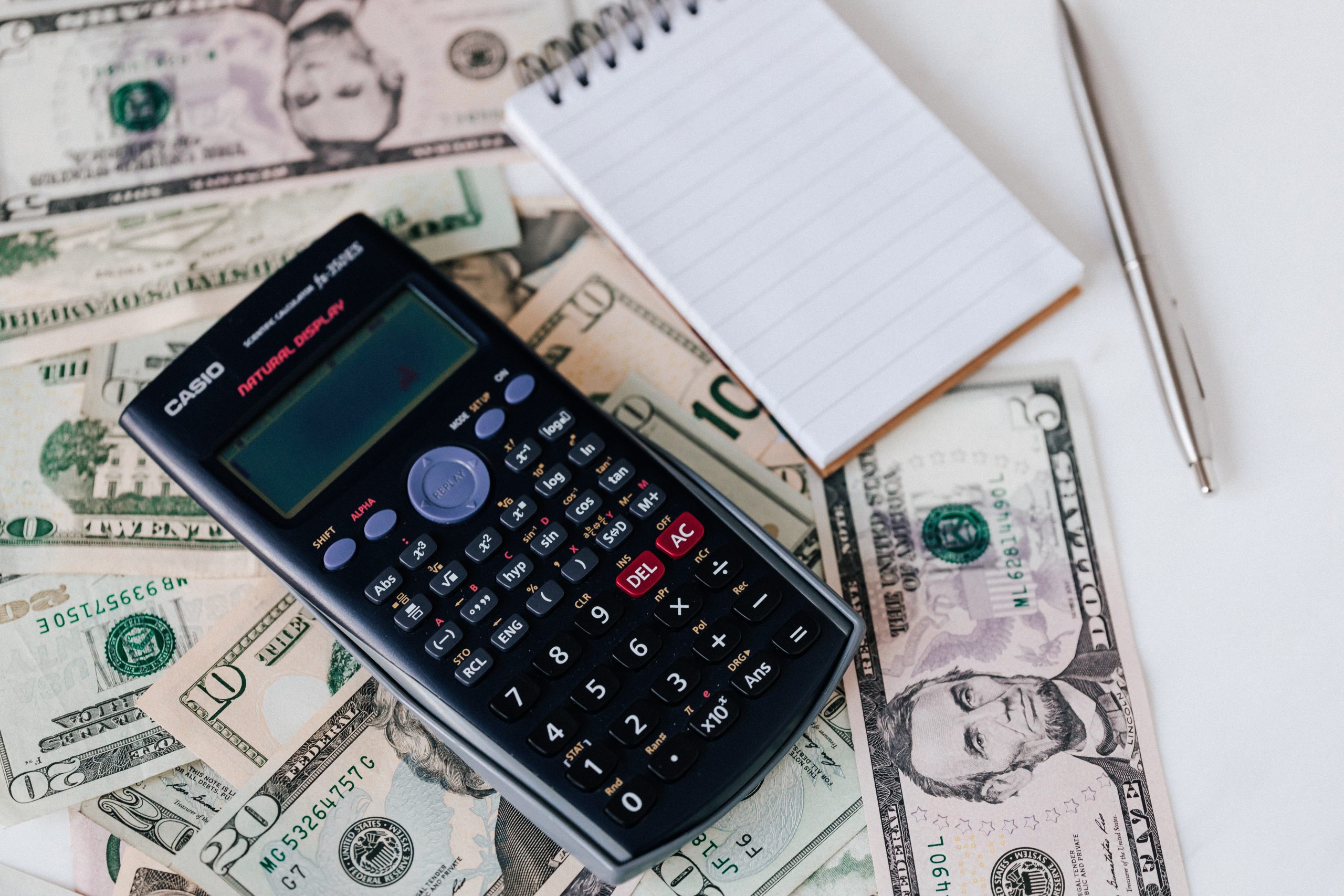 Stack of cash with a calculator: 7 common finacial mistakes