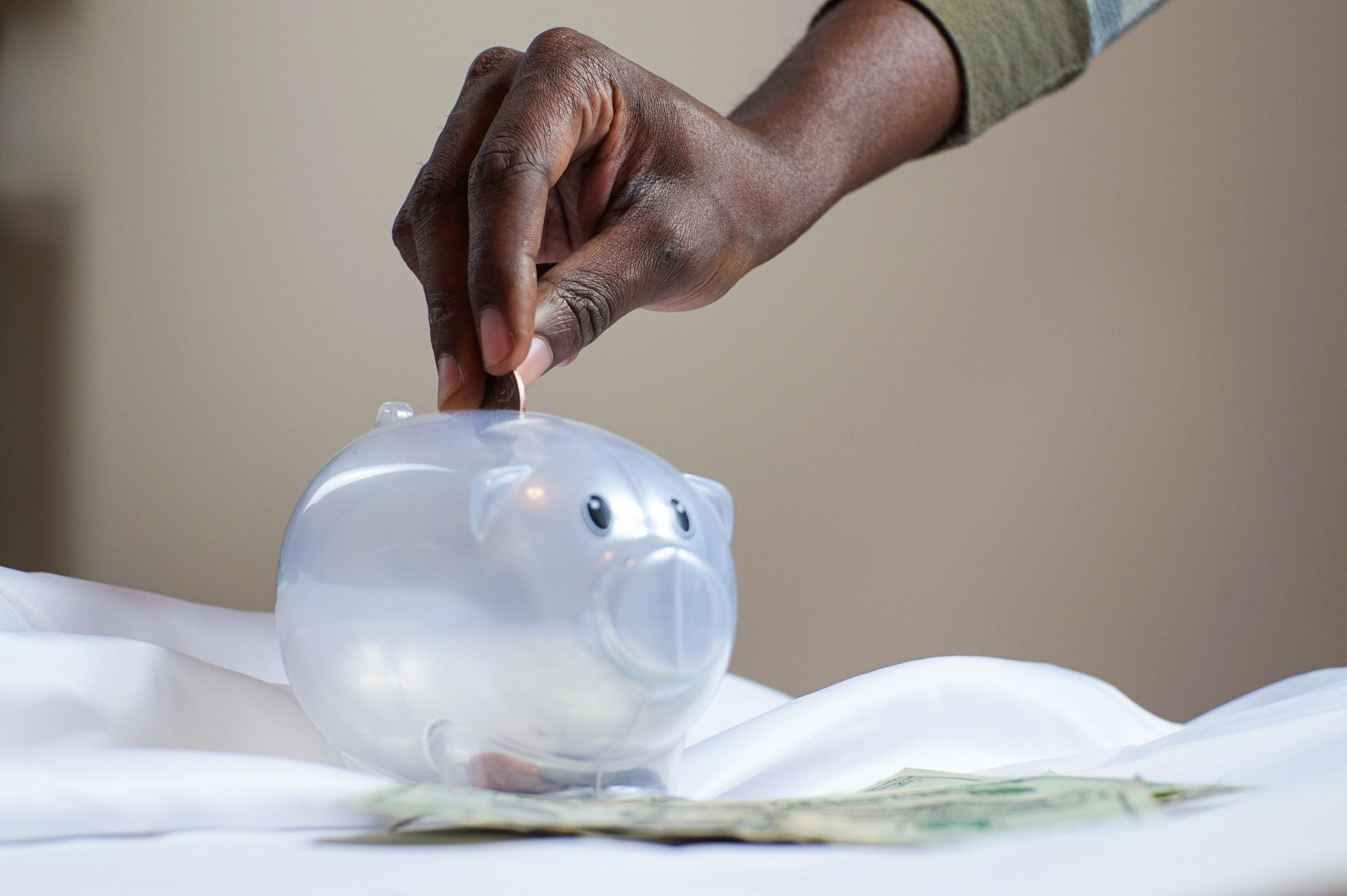 hand putting coin into piggy bank. 5 types of spenders