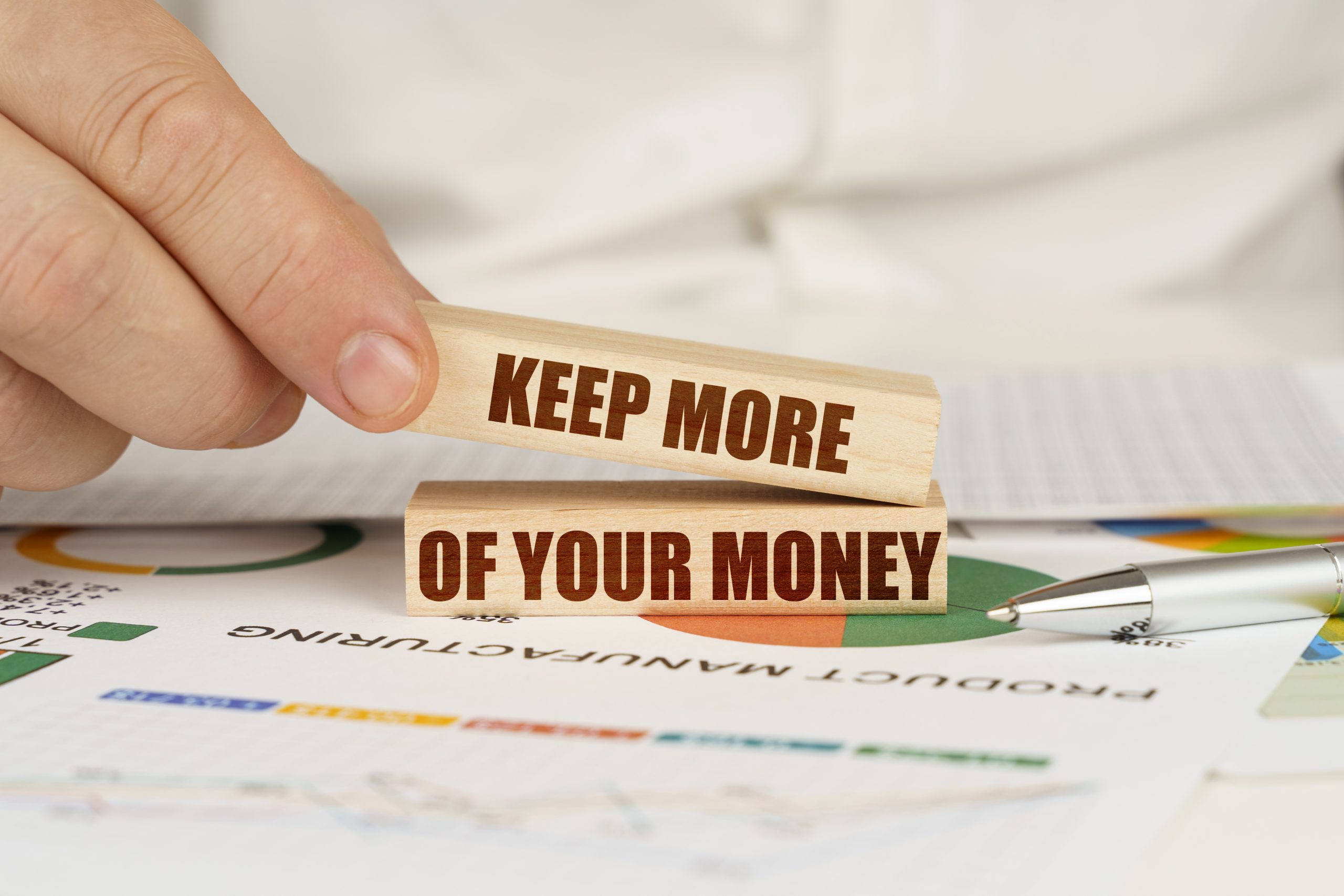 On the table are business charts in the hands of a wooden block with the inscription-Keep More Of Your Money-save paycheck